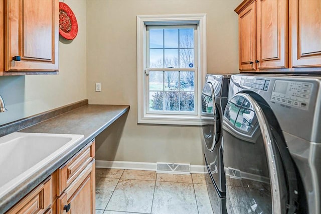 laundry room with cabinets, washer and clothes dryer, sink, and light tile patterned floors