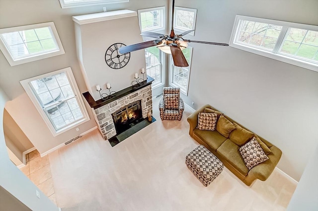 living room with ceiling fan, a towering ceiling, a fireplace, and a wealth of natural light