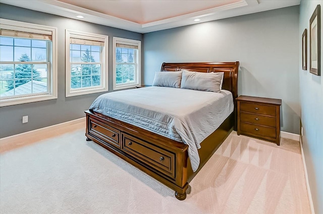 carpeted bedroom featuring a tray ceiling and multiple windows