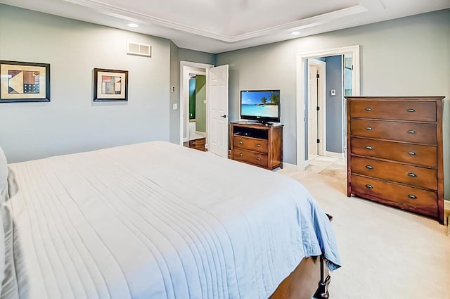 bedroom featuring light carpet, connected bathroom, and a tray ceiling