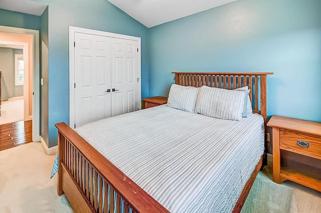 bedroom with light colored carpet, vaulted ceiling, and a closet