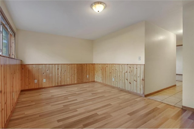 empty room with wood walls and light hardwood / wood-style flooring