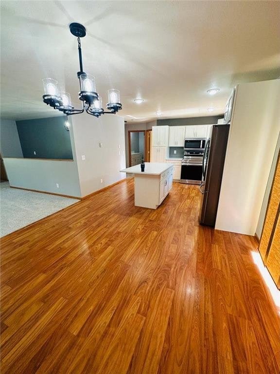 kitchen with a center island, light hardwood / wood-style flooring, decorative light fixtures, white cabinetry, and stainless steel appliances