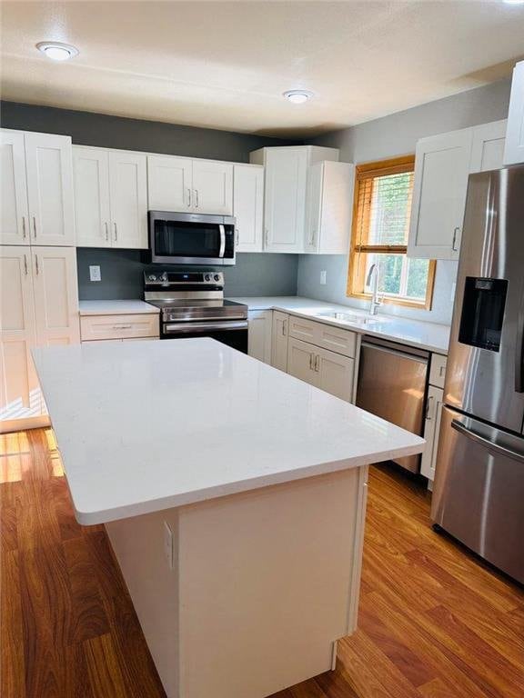 kitchen with a kitchen island, light hardwood / wood-style floors, white cabinetry, and appliances with stainless steel finishes