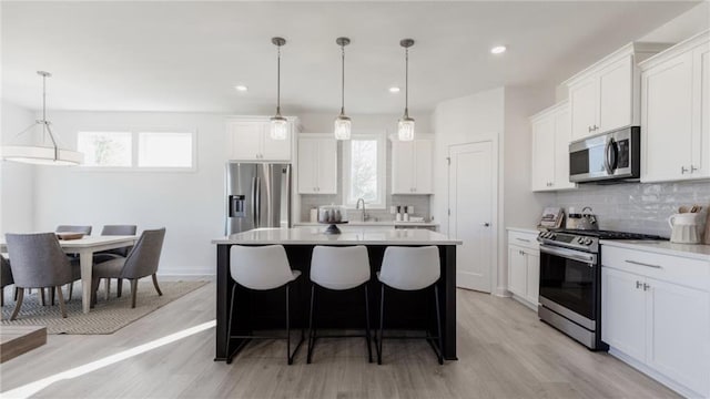 kitchen featuring white cabinets, a healthy amount of sunlight, stainless steel appliances, and pendant lighting