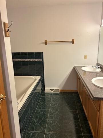 bathroom featuring tile patterned floors, vanity, and tiled bath