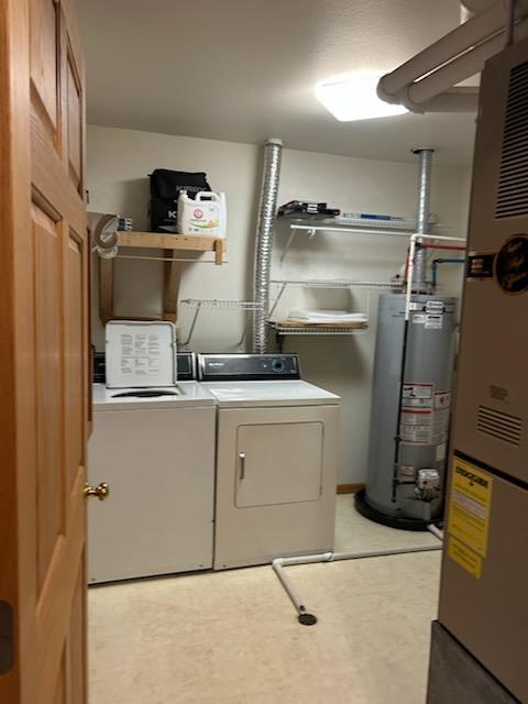 laundry area with gas water heater and washing machine and clothes dryer