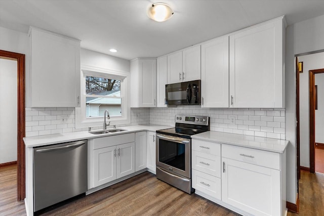 kitchen with decorative backsplash, appliances with stainless steel finishes, dark wood-type flooring, sink, and white cabinets