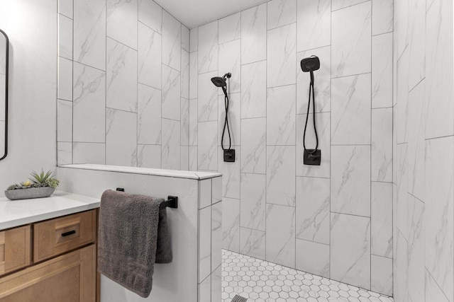 bathroom with tiled shower and vanity