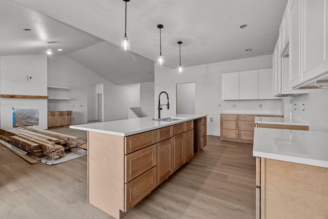 kitchen with sink, white cabinetry, hanging light fixtures, a large island with sink, and light hardwood / wood-style floors