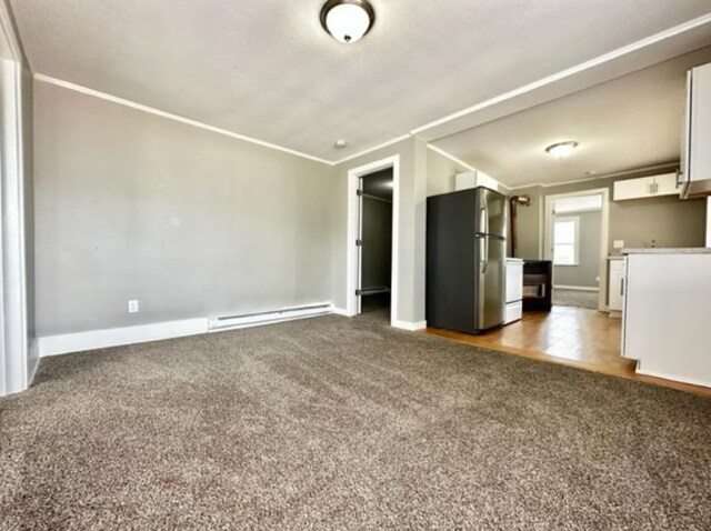 unfurnished living room with carpet flooring, crown molding, and a baseboard heating unit