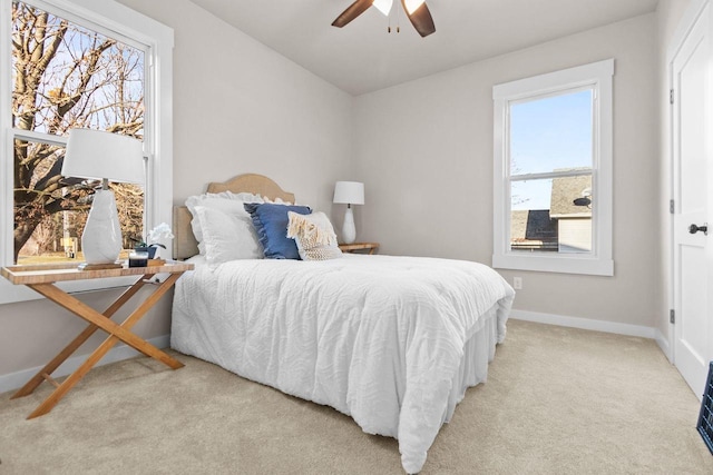 bedroom featuring ceiling fan, light carpet, and multiple windows