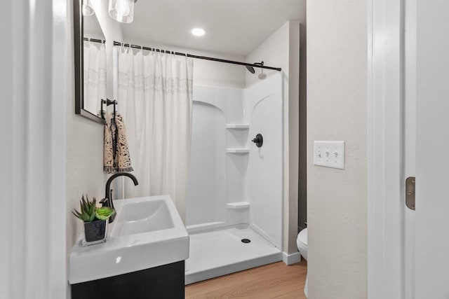 bathroom featuring vanity, toilet, wood-type flooring, and walk in shower