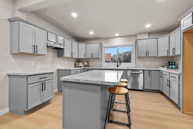 kitchen featuring stainless steel dishwasher, a kitchen island, gray cabinets, and light hardwood / wood-style floors