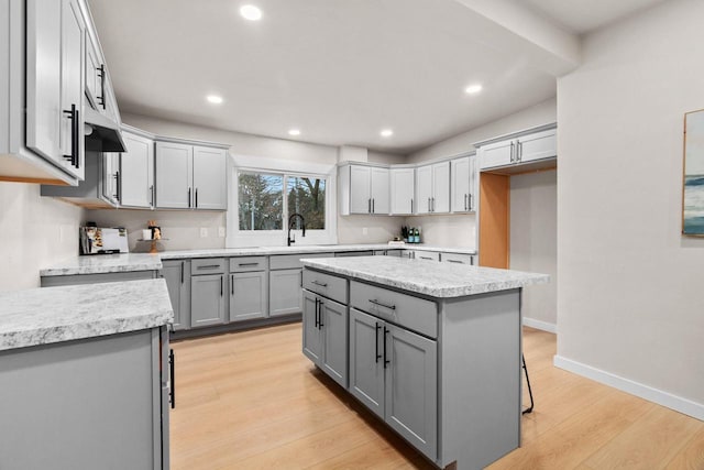 kitchen with gray cabinetry, sink, a kitchen island, and light hardwood / wood-style floors