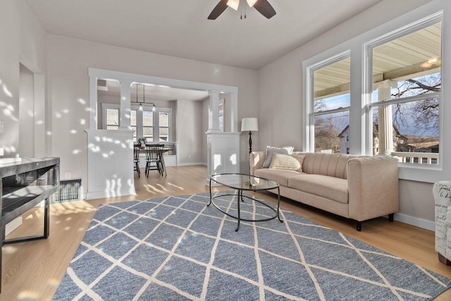 living room featuring decorative columns, ceiling fan, and hardwood / wood-style flooring