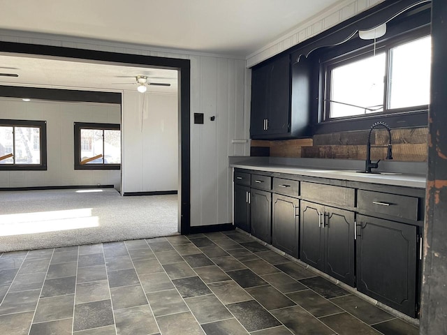 kitchen with dark colored carpet, ceiling fan, crown molding, and sink