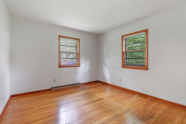 spare room featuring light wood-type flooring, a wealth of natural light, and a baseboard heating unit