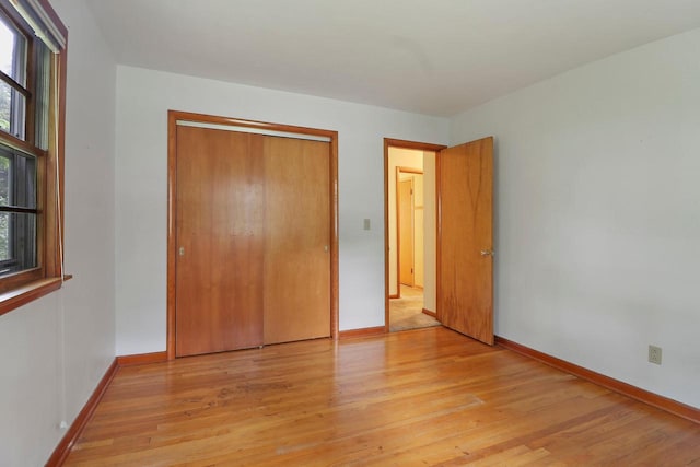 unfurnished bedroom featuring a closet, light hardwood / wood-style floors, and multiple windows