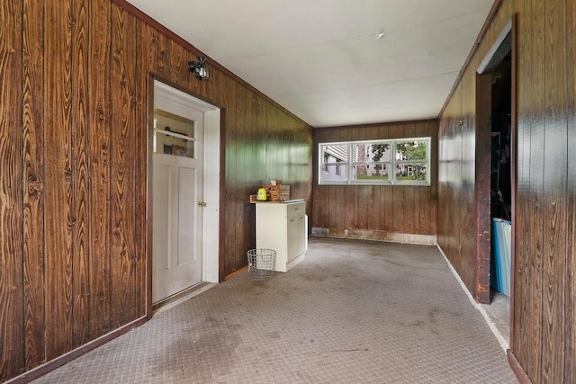 hall featuring carpet flooring and wooden walls