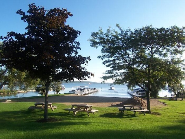 view of property's community featuring a lawn, a water view, and a boat dock