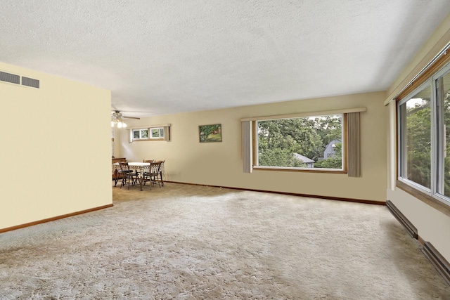 carpeted spare room featuring a textured ceiling, plenty of natural light, and ceiling fan