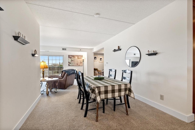 carpeted dining room featuring visible vents, baseboards, and a textured ceiling