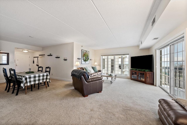 living area with baseboards, carpet flooring, visible vents, and a textured ceiling