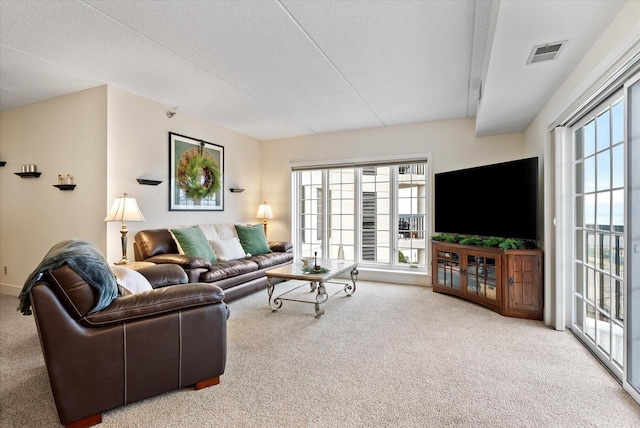 living area with carpet floors, visible vents, and a textured ceiling