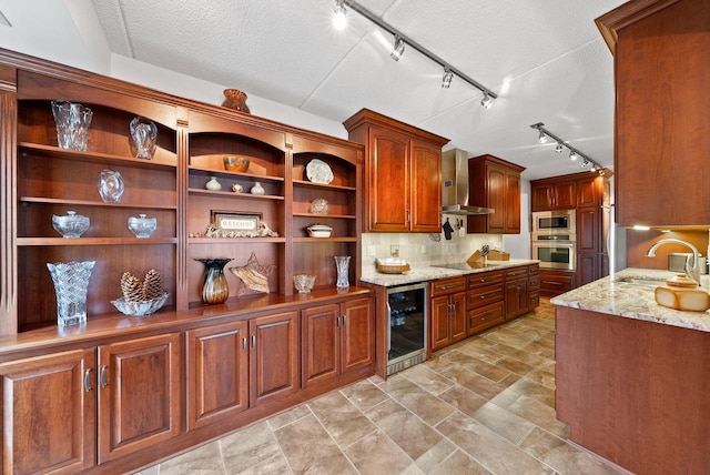 kitchen with wine cooler, a sink, wall chimney range hood, appliances with stainless steel finishes, and light stone countertops