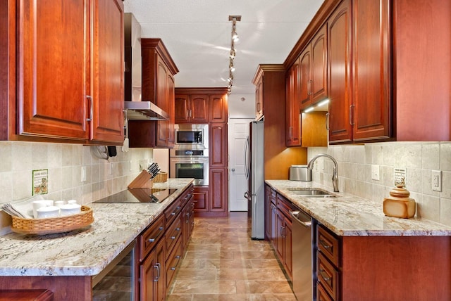 kitchen featuring stainless steel appliances, a sink, wall chimney range hood, light stone countertops, and pendant lighting