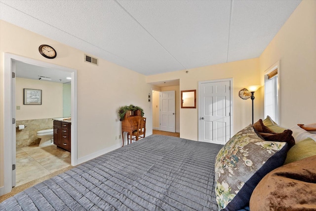 bedroom with a textured ceiling, ensuite bath, visible vents, and tile walls