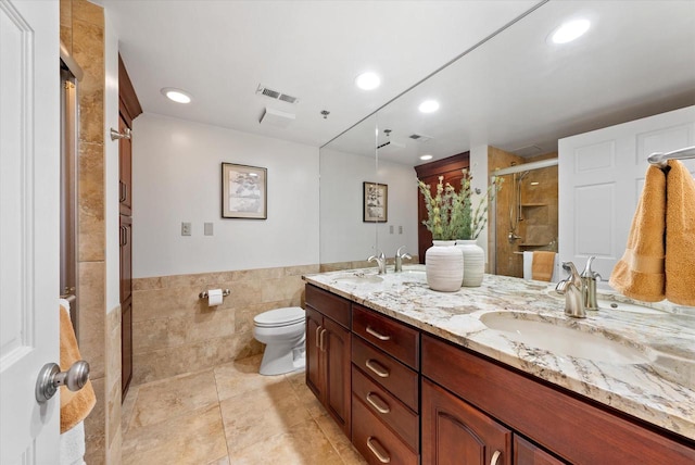 full bathroom featuring toilet, a sink, visible vents, tile walls, and double vanity