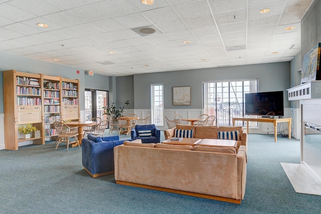 living room with a wainscoted wall, a drop ceiling, and carpet flooring