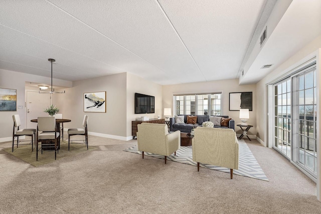 living room with a textured ceiling, baseboards, visible vents, and light colored carpet