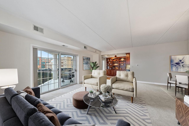 living room featuring light carpet, built in features, visible vents, and baseboards