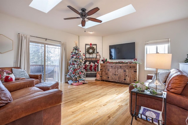 living room with hardwood / wood-style flooring, ceiling fan, and a skylight