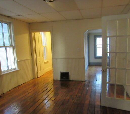 spare room with a paneled ceiling, dark hardwood / wood-style floors, and plenty of natural light