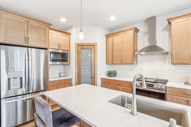 kitchen with decorative backsplash, appliances with stainless steel finishes, a breakfast bar, wall chimney range hood, and hanging light fixtures