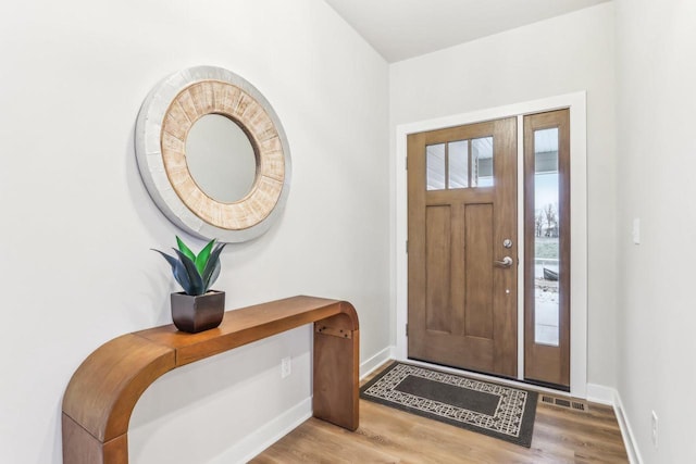 foyer entrance featuring light wood-type flooring, baseboards, and visible vents