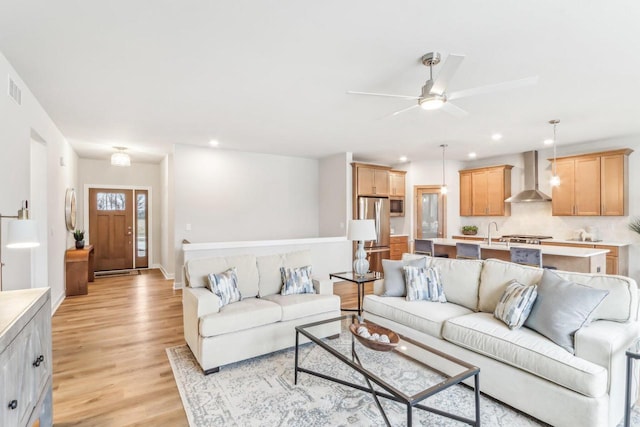 living area with recessed lighting, a ceiling fan, and light wood-style floors