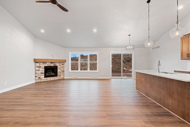 unfurnished living room with ceiling fan, dark wood-type flooring, sink, high vaulted ceiling, and a fireplace