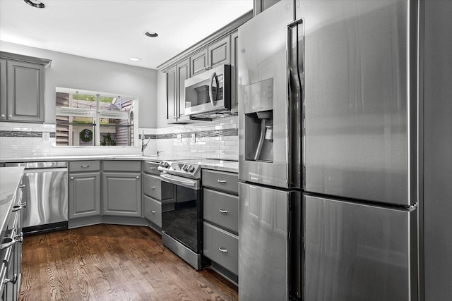 kitchen featuring gray cabinetry, dark hardwood / wood-style floors, backsplash, and stainless steel appliances