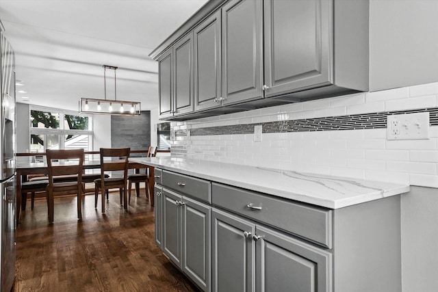 kitchen with gray cabinetry, decorative backsplash, hanging light fixtures, and dark hardwood / wood-style floors