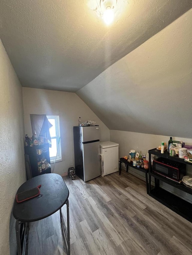 bonus room with lofted ceiling, a textured ceiling, and light hardwood / wood-style flooring