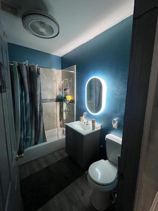 full bathroom featuring wood-type flooring, vanity, shower / tub combo, and toilet