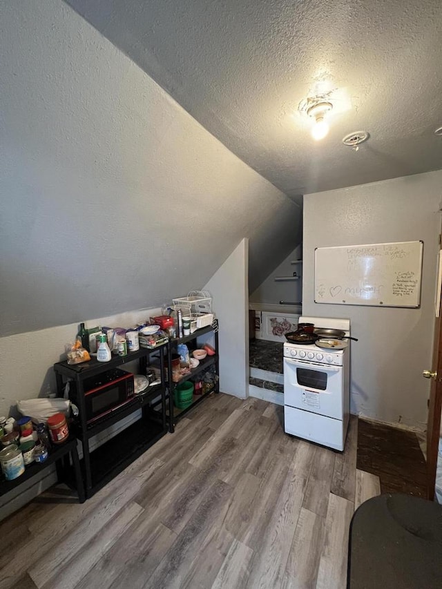 kitchen with vaulted ceiling, gas range gas stove, wood-type flooring, and a textured ceiling