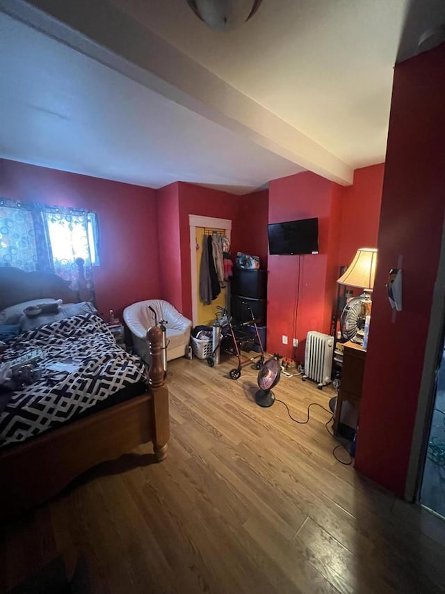 bedroom featuring a walk in closet, a closet, beamed ceiling, and hardwood / wood-style flooring