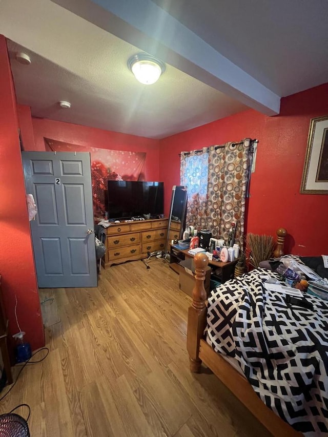 bedroom with hardwood / wood-style floors and beam ceiling