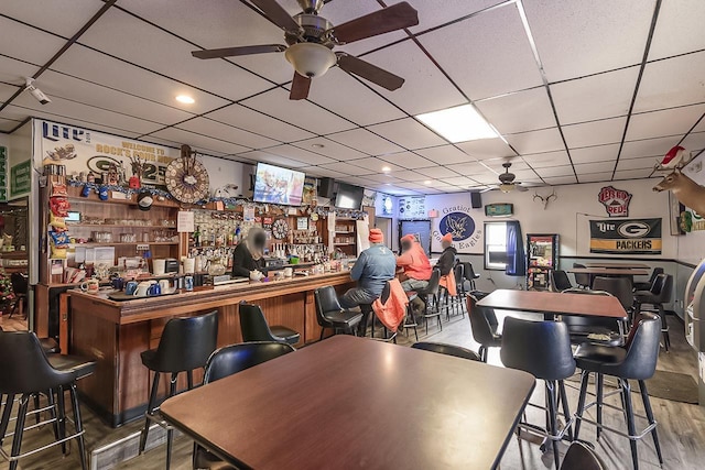 bar with hardwood / wood-style flooring, ceiling fan, and a drop ceiling